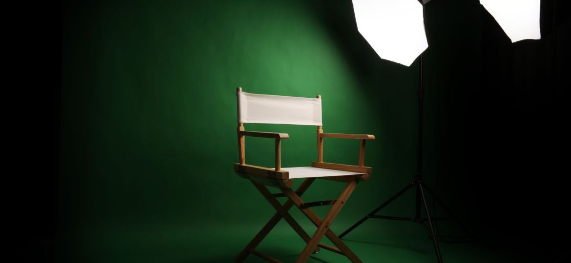Photo studio with green screen background and stool against ligh